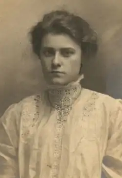A young white woman with hair in a bouffant style, wearing a white lacy blouse