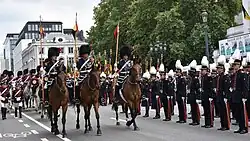 Soldiers in elaborate uniforms parade on horseback