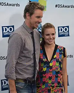Photo of Dax Shepard and Kristen Bell, where Shepard is a head taller, Bell is wearing a multi-colored dress