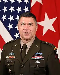 Head and shoulders photo of Major General Mark H. Landes, dress uniform, head and shoulders, in front of United States and First Army flags