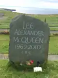 A carved stone with the inscription "Lee Alexander McQueen / 1969-2020 / CBE"