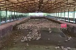 Archaeological site with remains of city walls under a modern protective roof