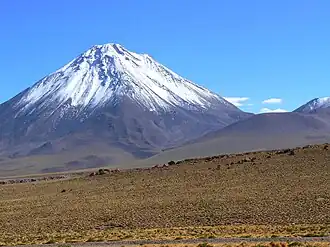 A snow-capped cone rises from a desolate landscape