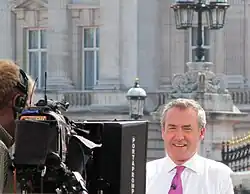 Sky News journalist Colin Brazier speaking to a camera in front of Buckingham Palace, London, UK