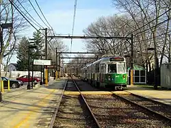 A green streetcar at a station
