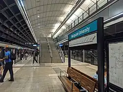 Picture of Macquarie University station. It consists of an underground platform with platform screen doors and a curved roof, similar to Macquarie Park station.