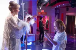 The screenshot shows Deborah Vance's wax figurine in Madame Tussauds. Ava holds Deborah's iPhone.