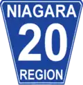 Niagara Regional Road 20 marker. While Niagara generally conforms to the standard Ontario "flowerpot" design, the markers are white-on-blue rather than the more traditional black-on-white and have rounded corners.
