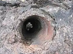 A circular hole in volcanic rock formed by a burned out tree trunk