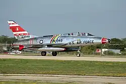 A North American F-100F single-engined two-seat jet fighter on runway.