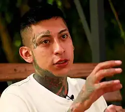 Headshot of Ocasional Talento against a green background and looking towards the right, gesturing