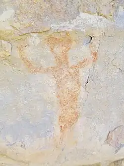 A red anthropomorphic figure with circular ear spools raising its arms.