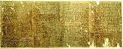A fragmented papyrus scroll slightly torn at the edges, with cursive hieratic handwriting in black ink