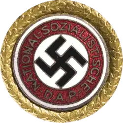 a circular golden badge with a central swastika