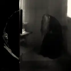 A grainy, black-and-white picture of Ethel Cain sitting with her head down and covered by her long hair.