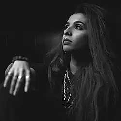 Lady Kash looking to the side with hand resting forward, black-and-white portrait