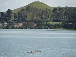 Puketutu Island's Pinnacle Hill, with a waka or canoe in the foreground.