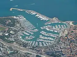 high-altitude view of a port, displaying many parked white boats
