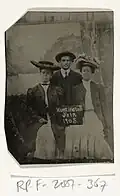 Portrait of a man and two women holding a signboard reading "Huntington Fair 1905"
