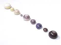 A collection of natural quahog pearls ranging from white to dark purple.