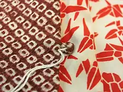 A closeup of the front of a haori (kimono jacket) made from burgundy-coloured kanoko shibori fabric.