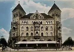 A postcard image with a large ornate brick building with a sign and awning at front saying "Romanisches Cafe"