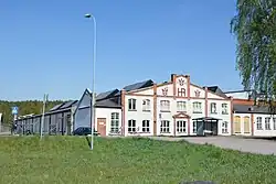 White and red building behind a grass field on a sunny day.