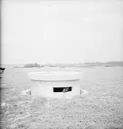 The turret of a Pickett-Hamilton retractable fort, fully raised and manned by a Bren-gun team of the Coldstream Guards, taken on a fighter airfield in Southern England.