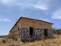 Abandoned building on Porto Palermo, contains former socialist message "THE DECISIONS OF THE 6th Congress of the PLA WORK PROGRAM (...)" (VENDIMET E KONG. 6te PPSH PROGRAM PUNE (...))