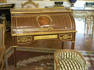 Roll-top desk of Marie-Antoinette; by Jean-Henri Riesener; 1784; oak and pine frame, sycamore, amaranth and rosewood veneer, bronze gilt; 103.6 x 113.4&nbsp;cm; Louvre[71]