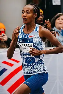 Hassan running at the 2023 Chicago Marathon. She is a black woman with dreadlocks, wearing a running outfit with her name on the front.