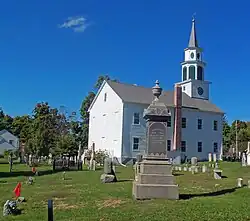 A white church, seen from the side slightly to its rear, with a cemetery in front