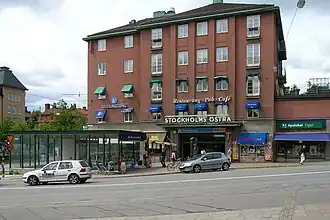 The red building of Stockholm Östra station and the entrance to the Stockholm Metro in front of it to the left