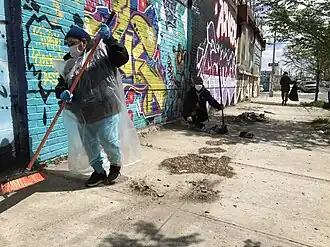 Street sweepers clearing a New York sidewalk of dust and dirt using brooms