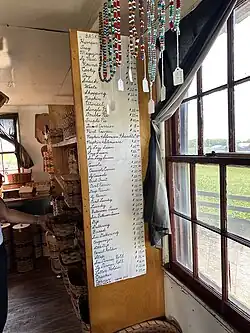 Handwritten price list beside a window. Note the curtain hung permanently in place and tucked back to open, rather than being drawn; this is unique to Swartzentrubers.