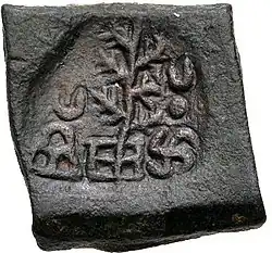 A coin of Takshashila, portrays a tree flanked by a hill surmounted by a crescent and a Nandipada above a swastika.[29]