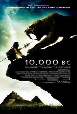 A prehistoric man wielding a spear crouches at the edge of a cliff, face-to-face with a saber-toothed tiger. A landscape featuring pyramids is seen in the background.