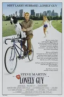 A man riding a bicycle with a dog balanced in front, and a woman runs behind them.