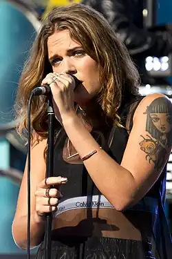 A woman with brown hair holding a microphone.
