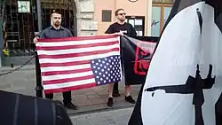 Two young men holding An American flag upside down