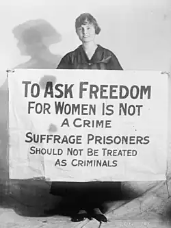 Photograph of a woman with a sign that reads "To ask freedom for women is not a crime. Suffrage prisoners should not be treated as criminals."
