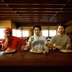 The three brothers sitting side by side eating waffles at a dining table
