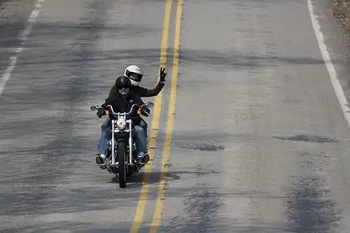 A motorcycle passenger using a V sign.