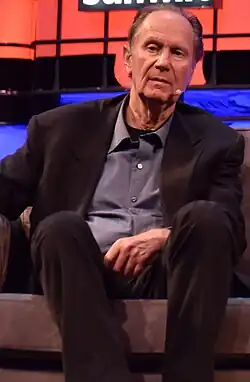 Full-body shot of Bonderman, an elderly man during a Web Summit conference.