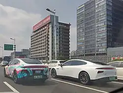 An itasha in Shanghai, China with Miku on a Xpeng P7 next to a regular Xpeng P7