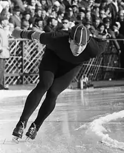 Yevgeny Grishin skating, leaned over while doing so. Pictured in black and white.