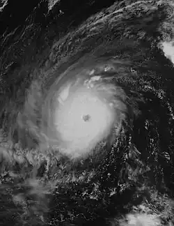 A nighttime satellite photograph of a very powerful tropical cyclone over the Western Pacific. The storm contains a dense eyewall holding an eye. Cirrus clouds point outward from the north, indicating outflow.