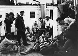 Scene from Zew morza (1927), featuring Stefan Szwarc (standing, with pipe) as Rudolf Minke, Henryk Rzętkowski (in striped shirt) as Smuggler, and Michał Halicz (right, leaning) as Gang member