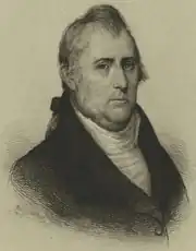 Print shows an unsmiling man in a dark coat with a white shirt. His signature is below.