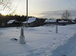 Ośnieżone drewniane domy, na pierwszym planie zawiana śniegiem droga